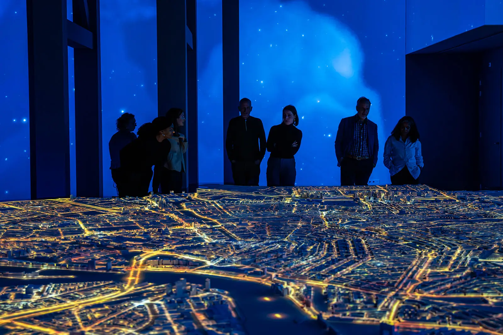 Visitors around the illuminated Amsterdam in Motion city maquette